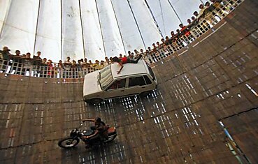 Каскадеры выполняют трюк, двигаясь на мотоциклах и автомобилях по «Стене смерти» в Дели