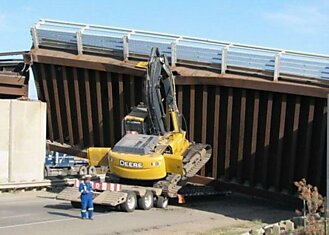 Водитель трала не рассчитал габариты моста и зацепил его.